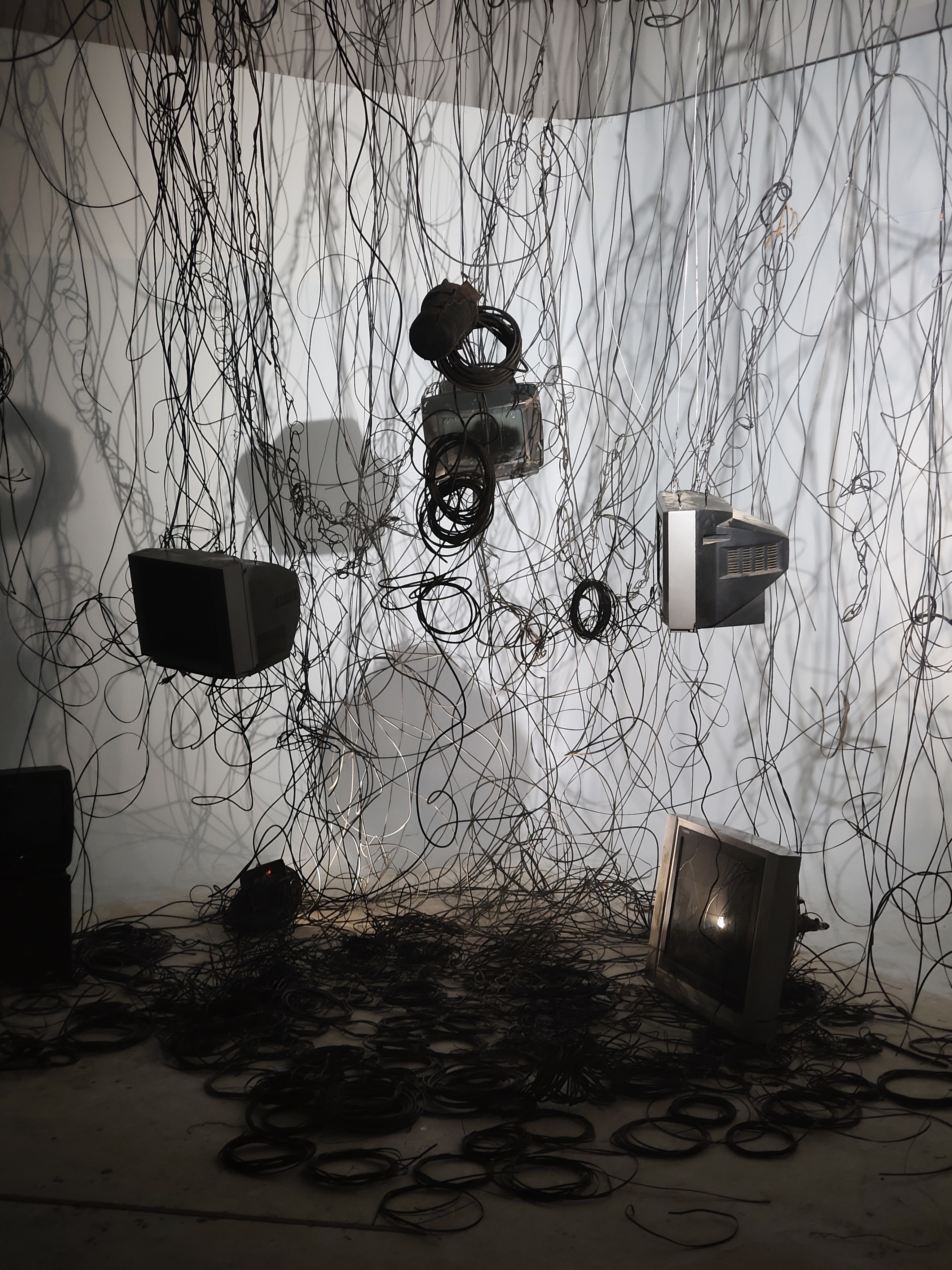 The real wires merge with the projected lines like signals from a TV screen, weaving together past visions and memories. They symbolize how urbanization and technology wrap around human life in Nepal,